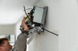 © DimaBerlin - Man technician worker in uniform fixing repairing apartment air conditioner, installing wall-mounted mini split. AC unit maintenance concept