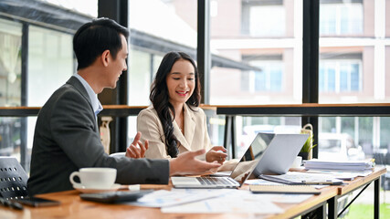 An Asian businessman is sharing his ideas and discussing work with a female colleague