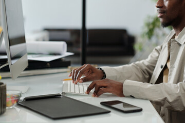 Aufkleber - Close-up of young African American designer typing on computer keyboard while sitting by desk and working with graphic sketches