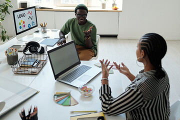 Aufkleber - Young African American male webdesigner talking to confident female colleague explaining her viewpoint about creating new website