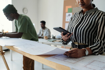 Aufkleber - Close-up of young female architect with smartphone taking photo of sketch on blueprint while standing against male coworkers