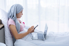 A Asian Women Disease Mammary Cancer Patient Hold Pick Up Smartphone Casual Working With Laptop Computer With Pink Ribbon Wearing Headscarf On Bed In The Bedroom At The House,healthcare,medicine
