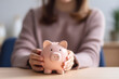 © Meta - A professional businesswoman holds a piggy bank, representing fiscal responsibility, wise financial decision-making, and the importance of financial stability in the business world. Generative AI