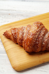 Wall Mural - Freshly baked croissant with powdered sugar on wooden board