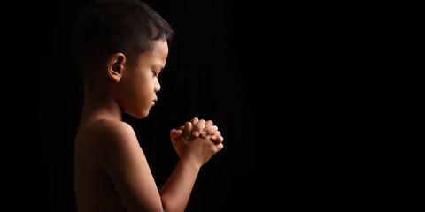 Portrait of praying boy on dark background