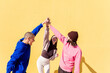 joyful young people high fives and having fun together on yellow background, concept of friendship and happiness, copy space for text