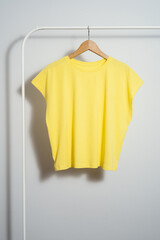 Wall Mural - Yellow t-shirt mockup on wooden hanger hanging on a clothes rack