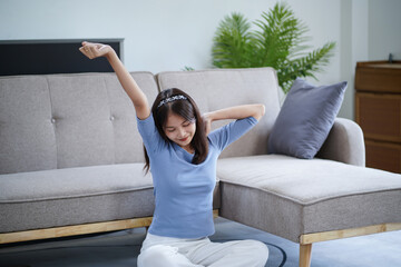 Beautiful Asian woman Stretching In cozy living room enjoy lazy weekend at home relaxing and health concept.