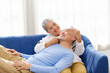 © artitwpd - Portrait of happy Asian senior couple living together, hug, touching and embracing with a smile on the sofa in the living room. Retirement living together at home.