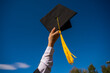 © Михаил Решетников - Close-up of a woman's hand with a graduation cap against the blue sky.