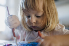 Cute Little Girl Painting With Tempera Paint Using A Paintbrush.