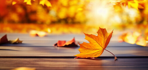Poster - Beautiful orange leaf on a wooden table in the autumn park. Natural autumn background with blur.