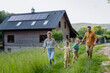 © Halfpoint - Happy family in front of their house with solar panels on the roof.