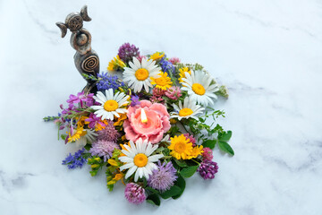 Triple Goddess figurine with candle and colorful flowers on abstract marble background. Symbol of the Triune Moon. esoteric ritual for Litha, Midsummer. witchcraft, wiccan spiritual practice. top view