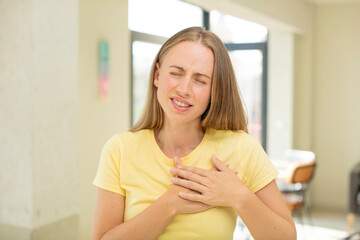 Wall Mural - pretty blond woman looking sad, hurt and heartbroken, holding both hands close to heart, crying and feeling depressed