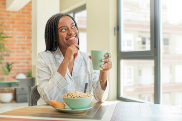 Wall Mural - black afro woman smiling with a happy, confident expression with hand on chin. breakfast concept