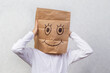 A child with cardboard boxes on his head, on which a smile is drawn with a marker. The concept of holiday shopping, moving.