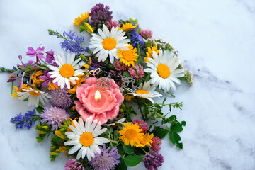 candle with pentacle amulet and colorful flowers on abstract marble background close up. esoteric ritual for Litha, Midsummer holiday. witchcraft, wiccan spiritual practice. top view