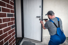 Professional Worker Locksmith Repairs Front Door Lock With Screwdriver