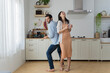© jittawit.21 - Overjoyed millennial husband and wife dancing in modern kitchen celebrate wedding anniversary at home together, happy young couple tenants have fun enjoy family