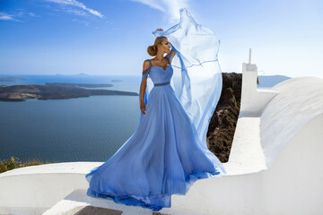 Elegant luxury evening fashion. Glamour, stylish elegant woman in long gown dress is posing outdoor in luxury resort in Santorini. Female model in amazing long dress. Vogue. Couture.