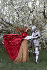 A red-haired girl says goodbye to a knight in a blooming garden