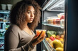 © Jasmina - Plus size woman looking in a fridge, searching for food while on a diet. Stressed, anxious and frustrated lady struggling with weight loss