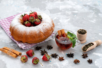 Wall Mural - a front view round cake with sugar powder red strawberries tea on the white desk berry fruit cake sweet