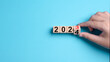 2024 Happy New Year eve wooden blocks flip change hand blue background. Countdown starting ending 2023 action schedule calendar strategy future vision. Business startup plan resolution celebration