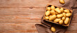 Crate with raw potatoes on wooden background with space for text