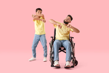 Wall Mural - Little boy and his father in wheelchair dancing on pink background