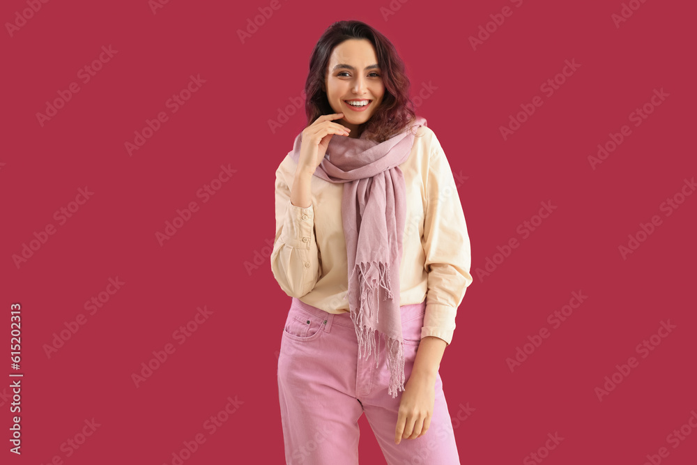 Stylish young woman in scarf on pink background