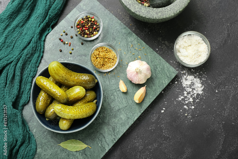 Bowl with tasty fermented cucumbers on dark grunge background