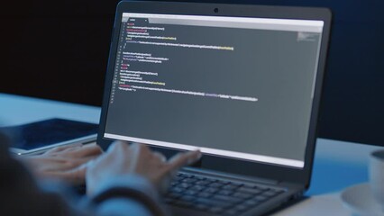 Wall Mural - panning right close up of unrecognizable person sitting at desk in front of laptop creating code in 
