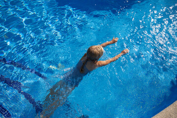 Child swims in the pool on a sunny summer day. Selective focus.