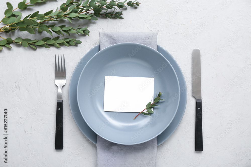Stylish table setting with blank card and plant branches on white textured background