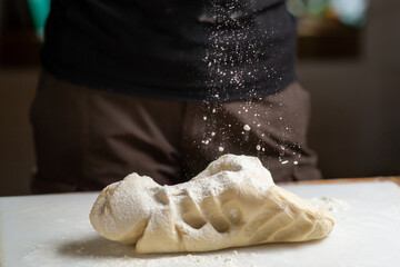 Dough on cutting board on which flour is poured. Preparation of bread, dough for various products.