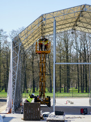 Canvas Print - Assembly of the metal frame tent storage hangar with the help of a self propelled scissor lift