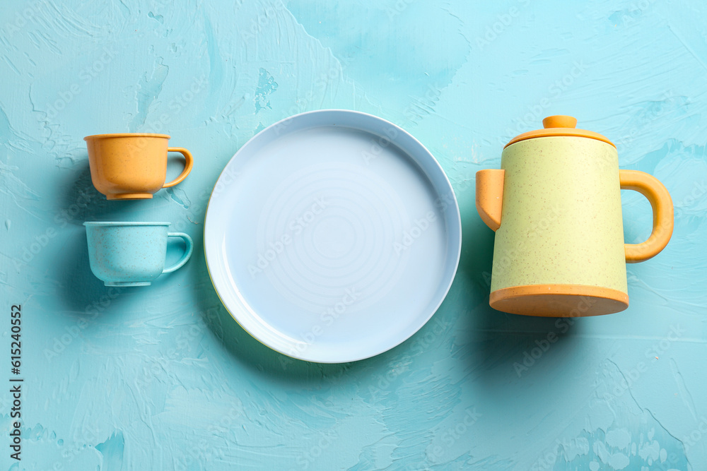 Plate with cups and teapot for baby on grunge blue background
