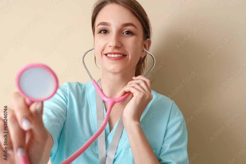 Female medical intern with stethoscope on beige background, closeup