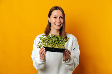 Cheerful smiling woman is holding some healthy sunflower micro greens.