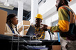 © DC Studio - Storehouse workers explaining logistics manager parcels storing system, talking at reception desk. African american men and woman warehouse operators team discussing stock supply chain