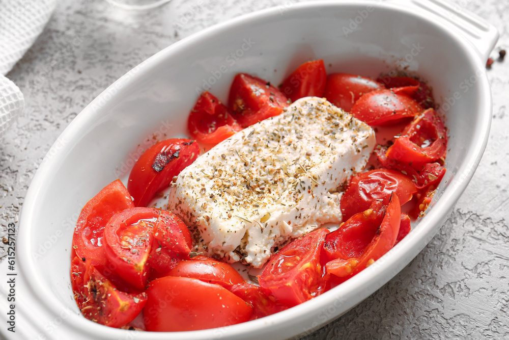 Baking dish with tasty tomatoes and feta cheese on grey background
