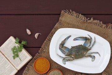 Wall Mural - Fresh crab on a white plate, how to prepare seafood, dark background, free space, for typing, top view