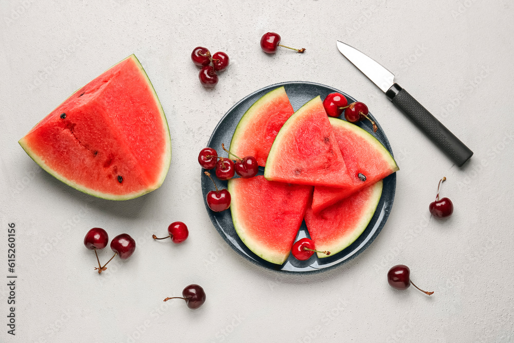 Plate with pieces of fresh watermelon and cherries on grey background