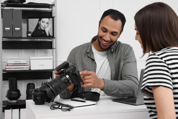 Canvas Print - Young professional photographer showing camera to woman in modern photo studio