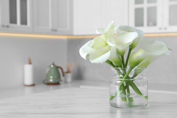 Canvas Print - Glass vase with beautiful calla lily flowers on table in kitchen. Space for text