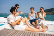 © Kawee - Group of diverse friend sit on deck of yacht while yachting together.