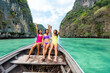 Group of Asian woman friends in swimwear sitting on the boat passing island beach lagoon in summer sunny day. Attractive girl enjoy and fun outdoor lifestyle travel on holiday vacation in Thailand.