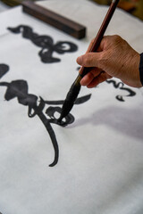 Wall Mural - An old Chinese calligrapher is writing brush characters, creating Chinese calligraphy works.
Translation: Spring comes, the god of wind arrives.